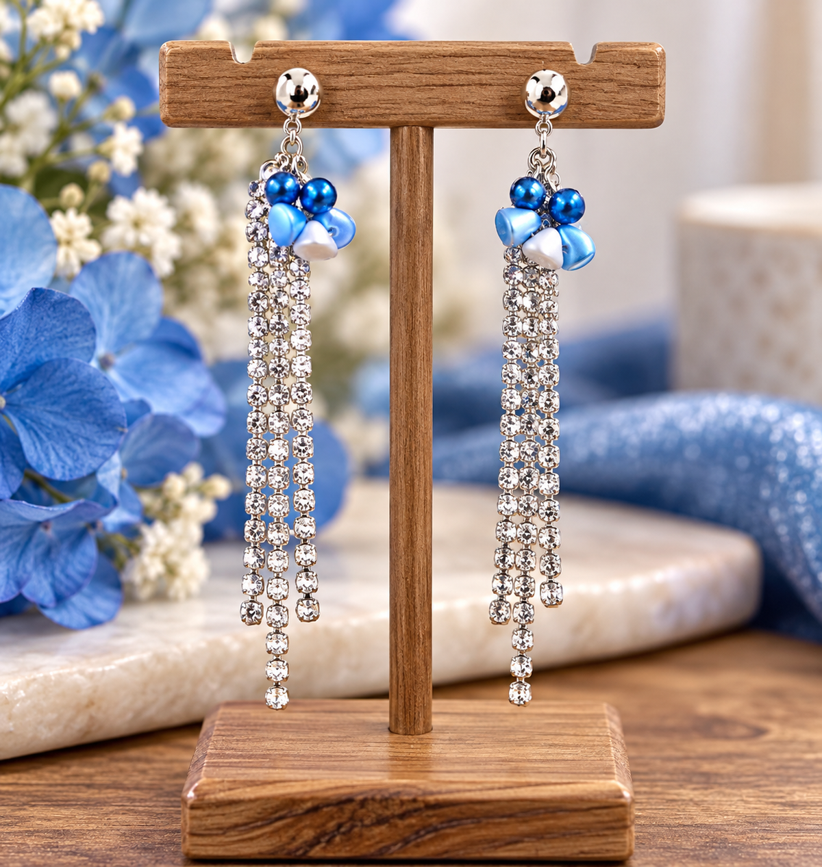 Rhinestone beaded earrings with blue beads on wooden display stand with blue flowers