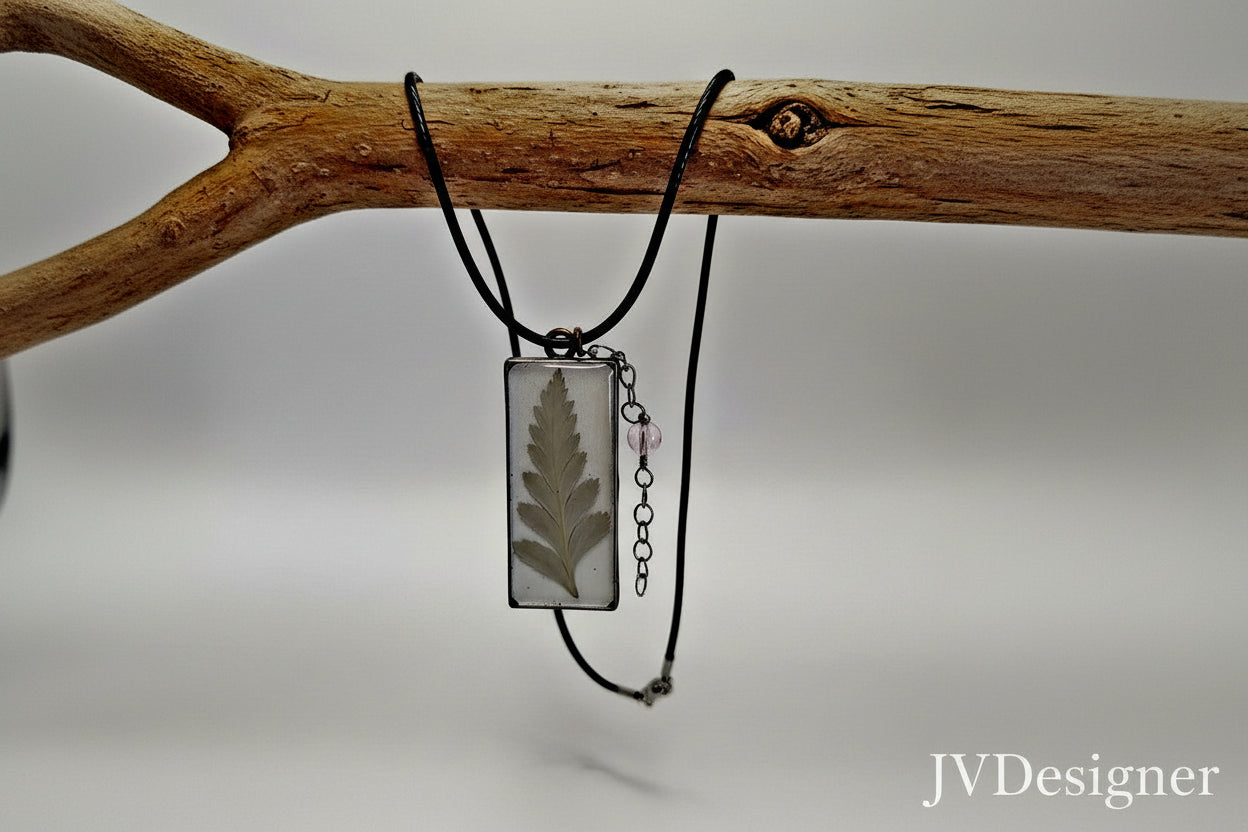 Necklace with a pendant featuring a pressed leaf on a wooden branch against a neutral background