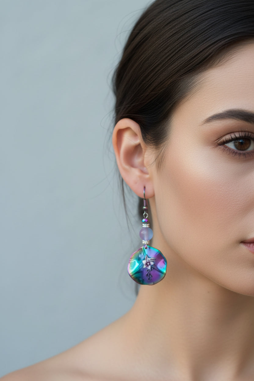 Multicolored beaded earrings held in a hand with a blurred background