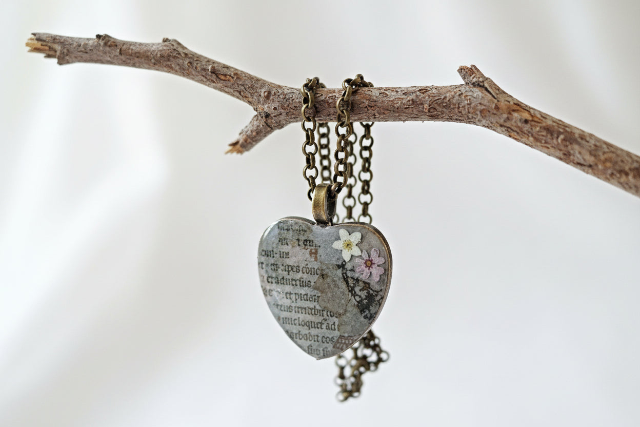 Heart-shaped pendant with floral design on a branch against a white background