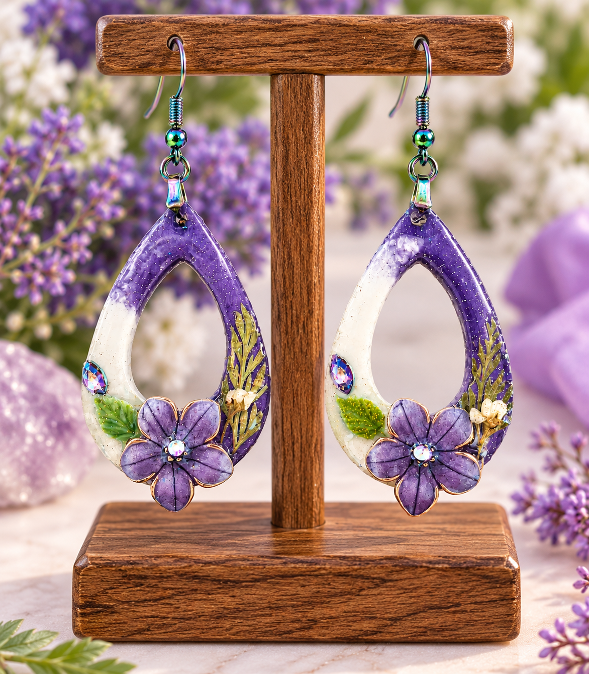 Purple floral resin teardrop earrings with pressed flowers on a display stand