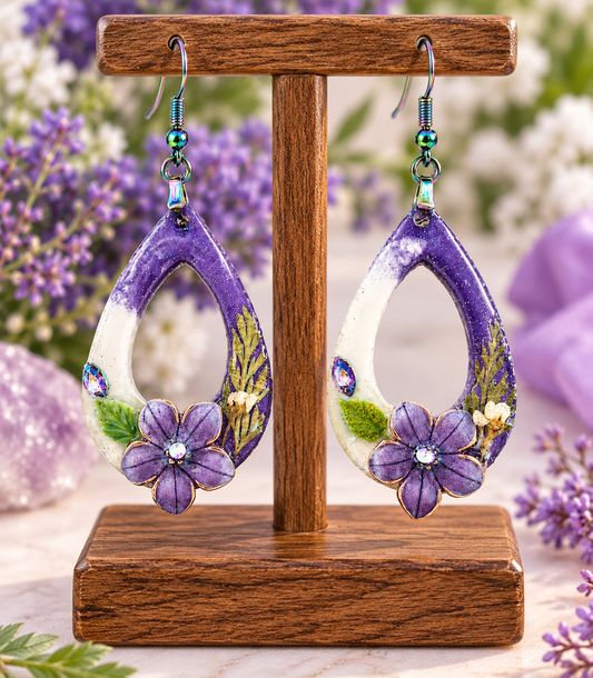Purple floral resin teardrop earrings with pressed flowers on a display stand