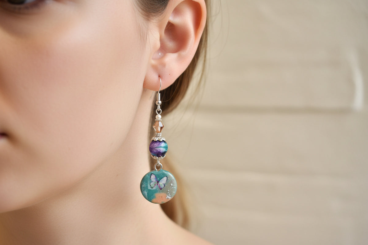 Pair of earrings with butterfly designs on a light background