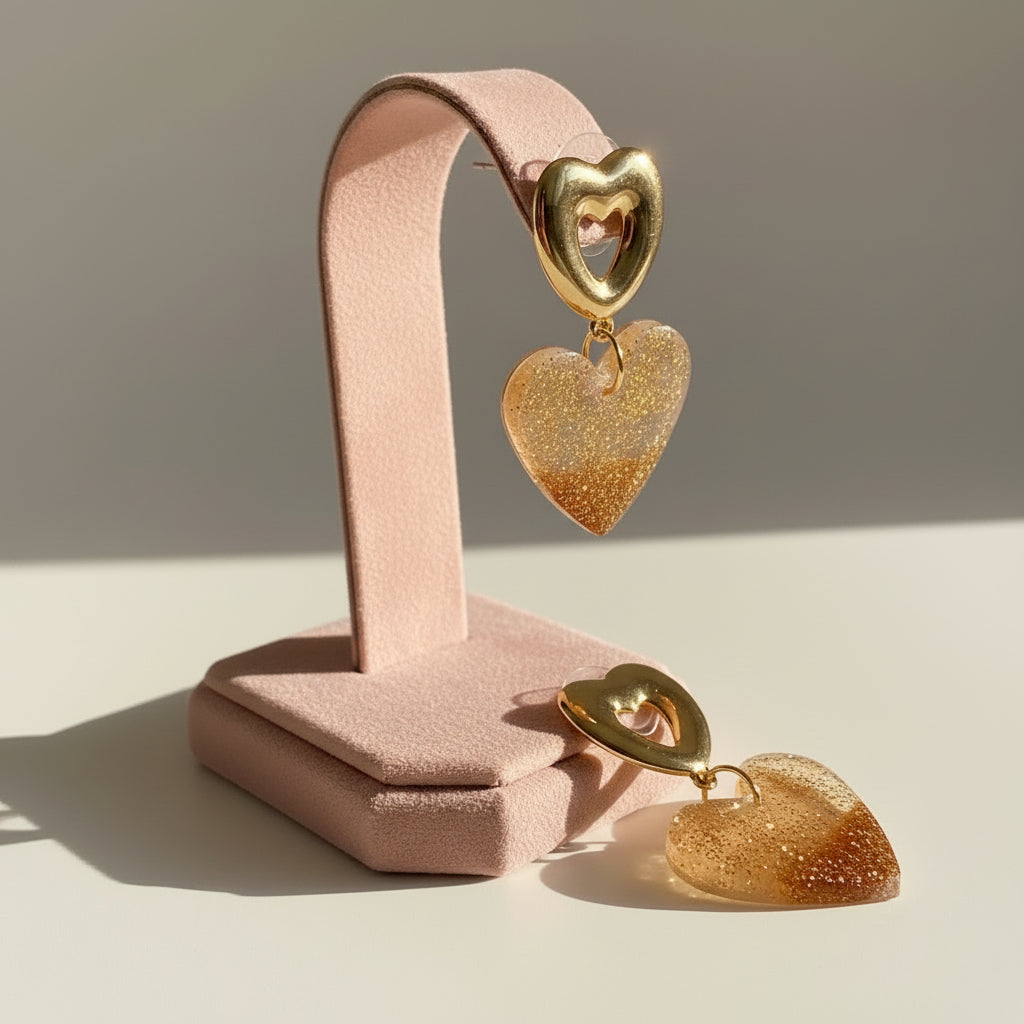 Heart-shaped earrings with gold glitter finish on a light background