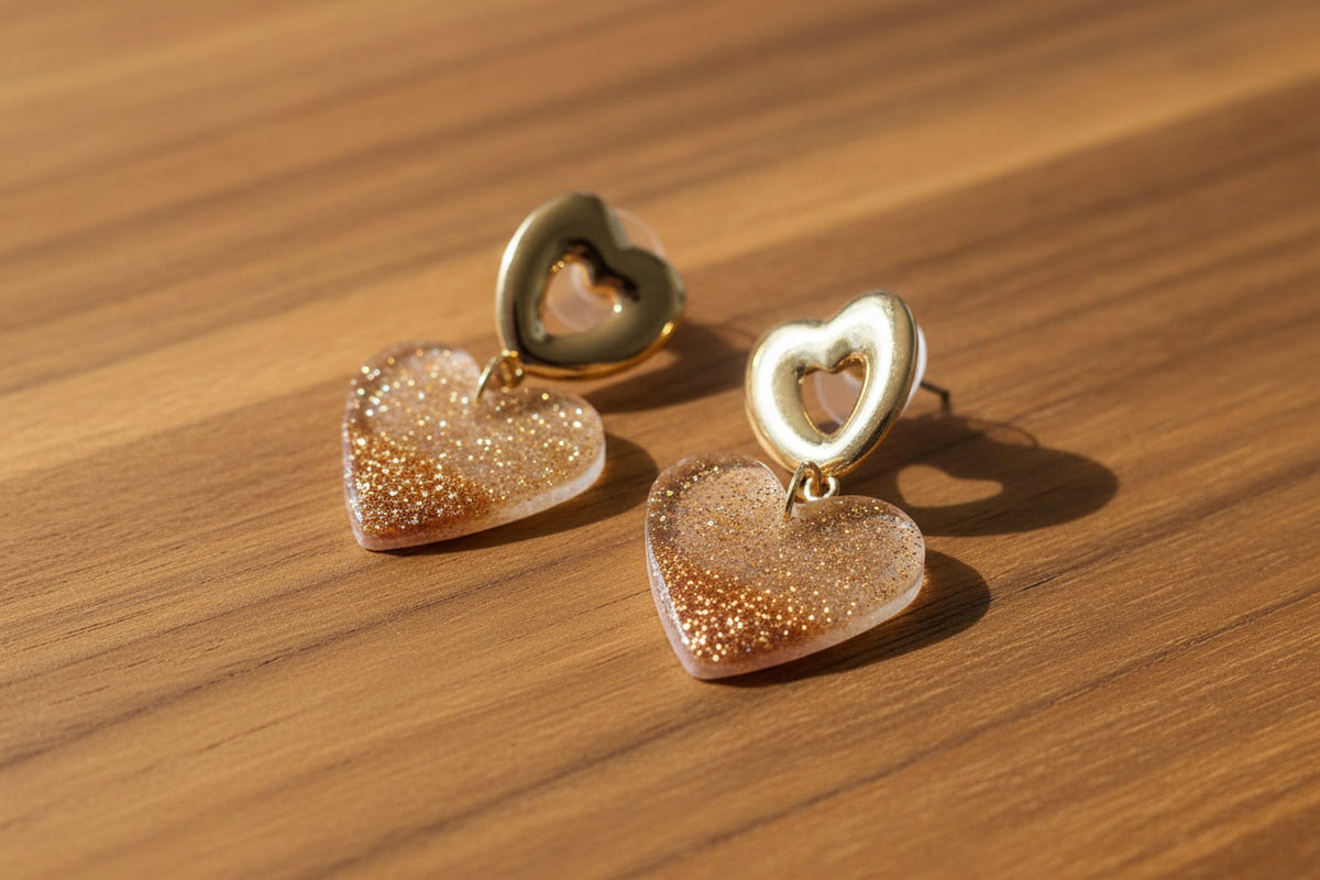 Heart-shaped earrings with gold glitter finish on a light background
