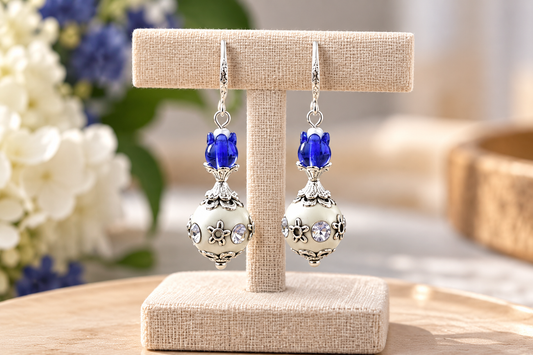 White and cobalt blue boho earrings with ornate silver beads on a display stand