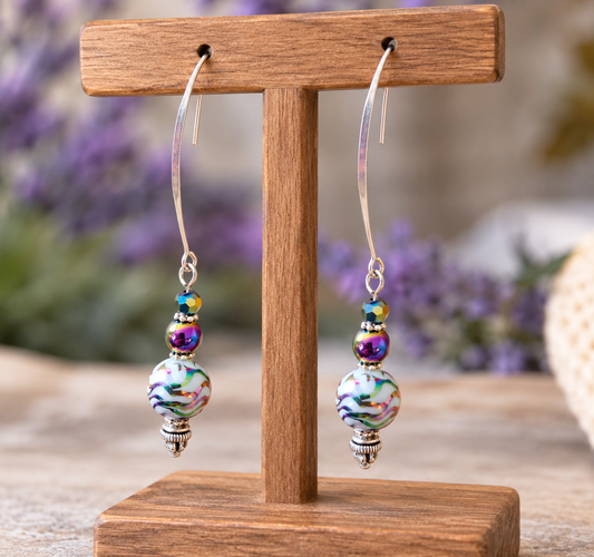 Handmade rainbow hematite dangle earrings with silver kidney hooks on display stand