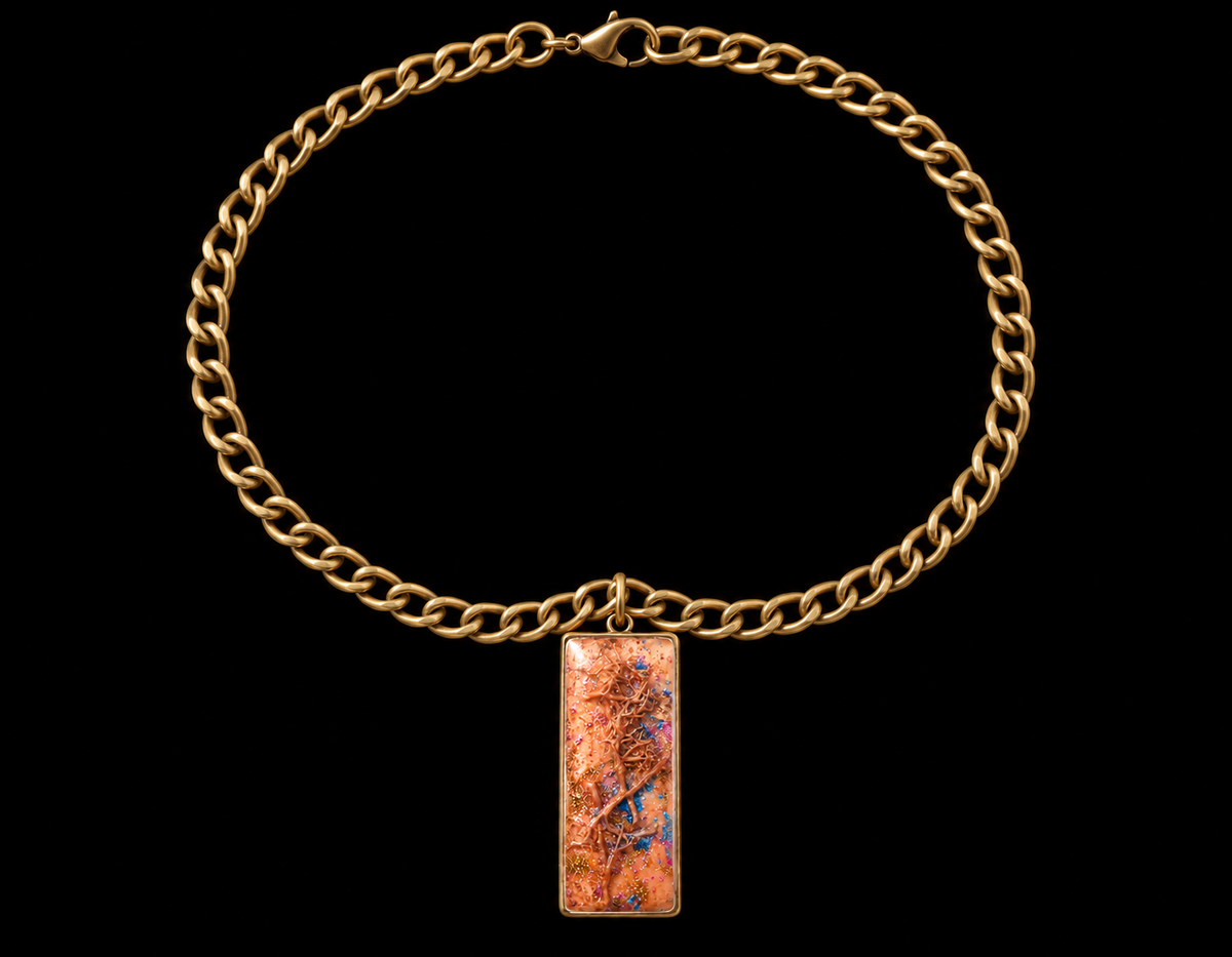A gold-toned curb chain necklace with a rectangular pendant featuring a textured, metallic copper-orange surface with fine blue and brown veining, set against a solid black background.