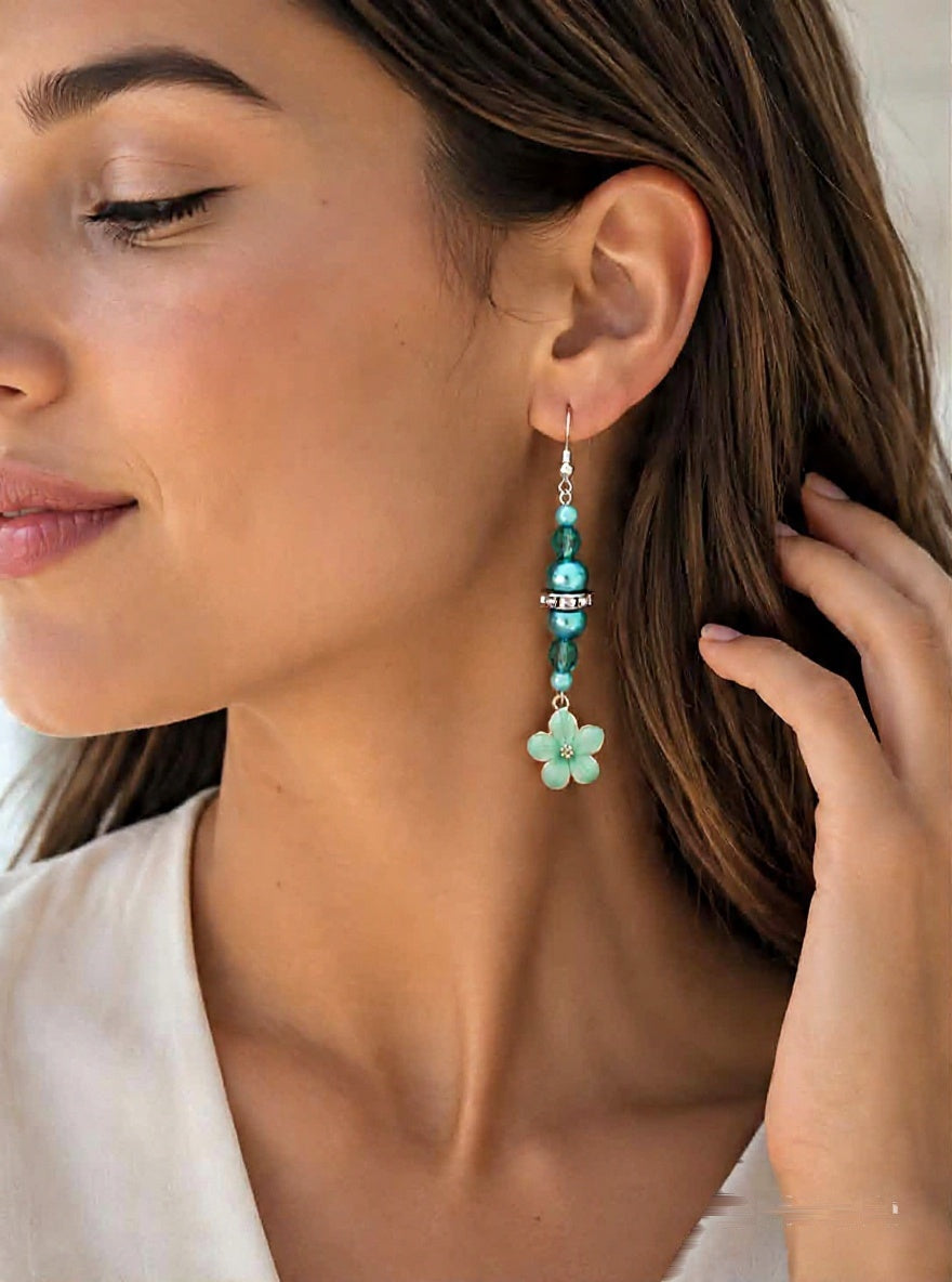 Woman wearing handmade turquoise enamel flower drop earrings with blue beads