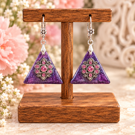 Purple rhinestone triangle earrings with pink crystal flowers on a display stand