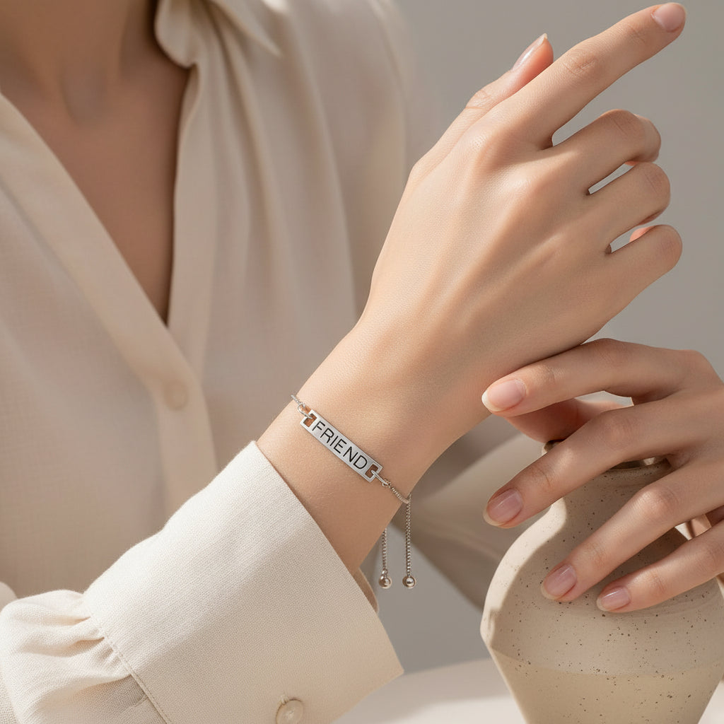 A silver adjustable slide chain bracelet with a rectangular bar engraved with the word 'FRIEND', displayed on pastel-colored circular paper backgrounds.