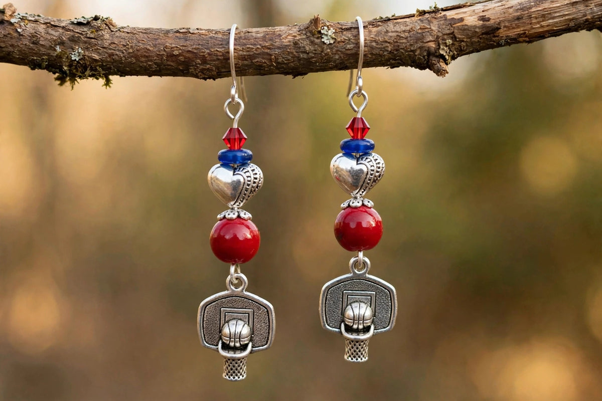 Silver basketball dangle earrings with red glass beads, blue spacers and Tibetan heart beads hanging from a branch