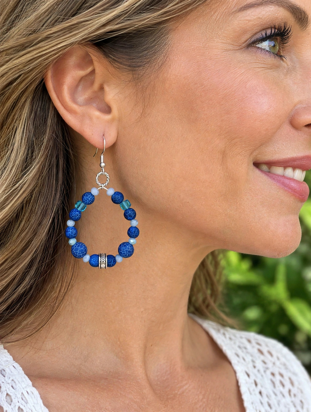 Woman wearing blue crackle bead hoop earrings with turquoise cube beads