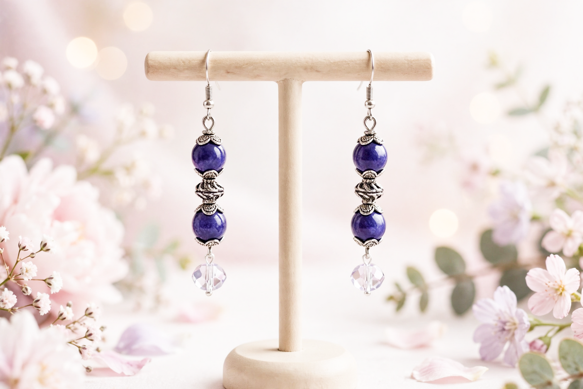 Handmade purple glass bead dangle earrings with silver accents and crystal drops on a wooden stand