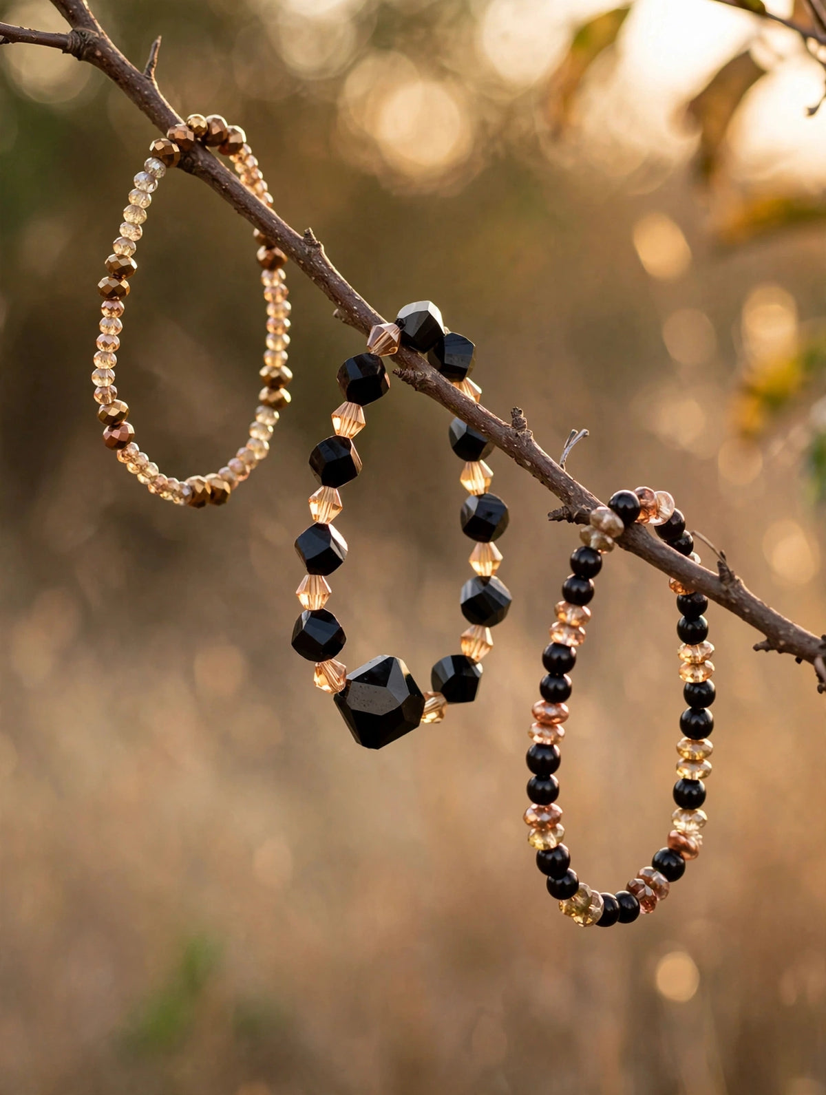 Set of 3 handmade black and gold glass bead stretch bracelets hanging on a branch