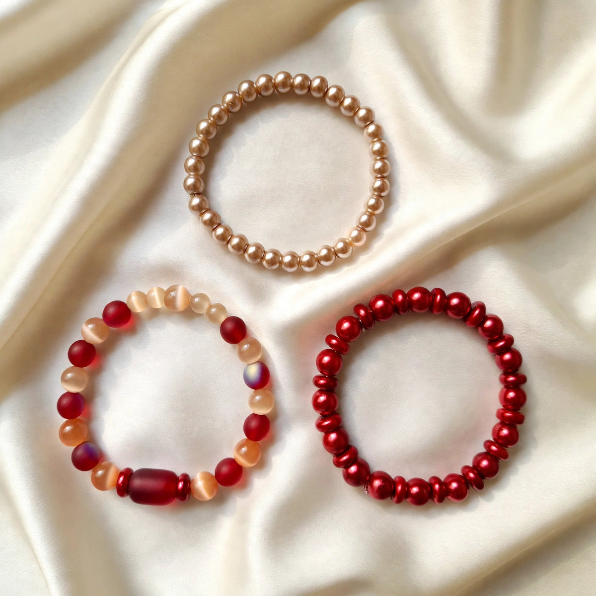 Set of 3 handmade burgundy, beige and red glass bead stretch bracelets in perfect circles on ivory silk