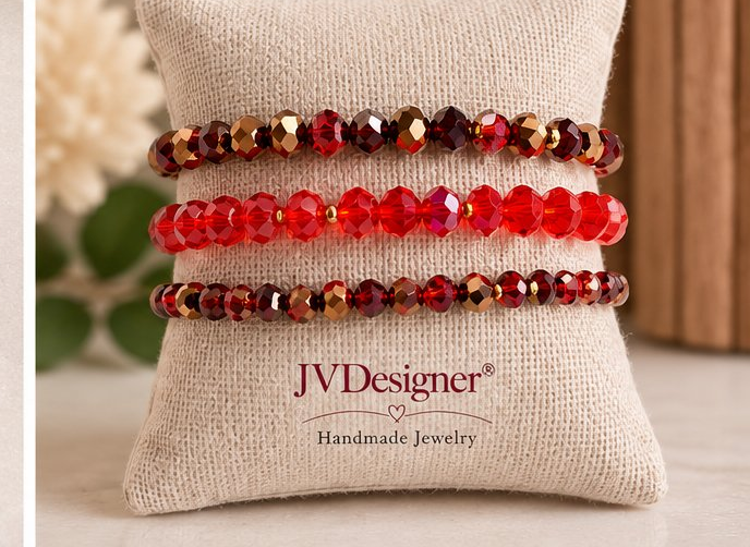 Three beaded stretch bracelets displayed on a beige fabric jewelry pillow. The bracelets feature faceted beads in red, deep burgundy, and metallic bronze/copper.