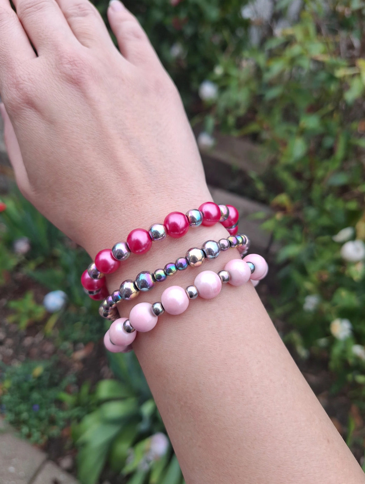 Pink pearl stretch bracelet set of 3 stacked on a wrist – hot pink, rainbow aura and blush beaded bracelets