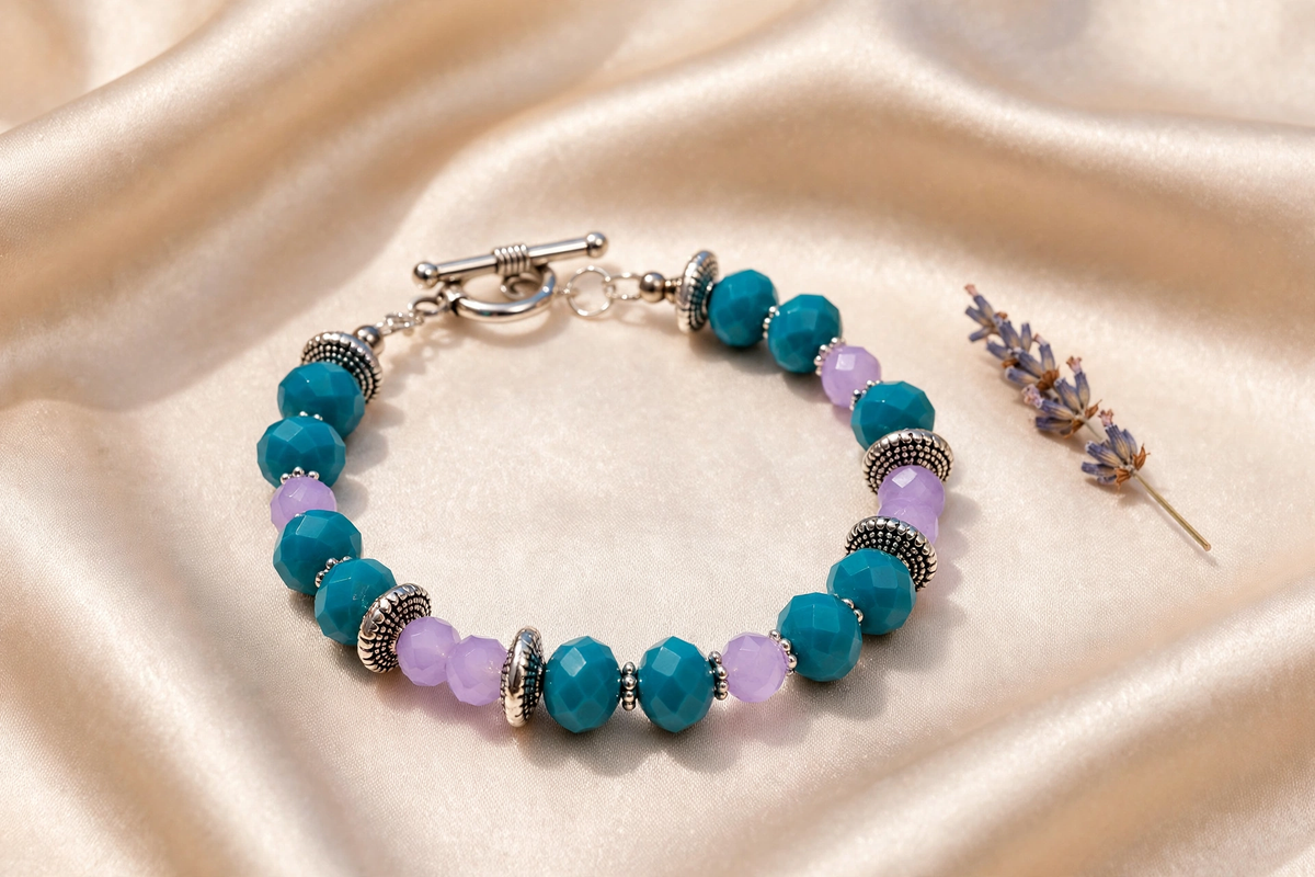 Handmade teal and lavender faceted bead bracelet with silver toggle clasp on marble
