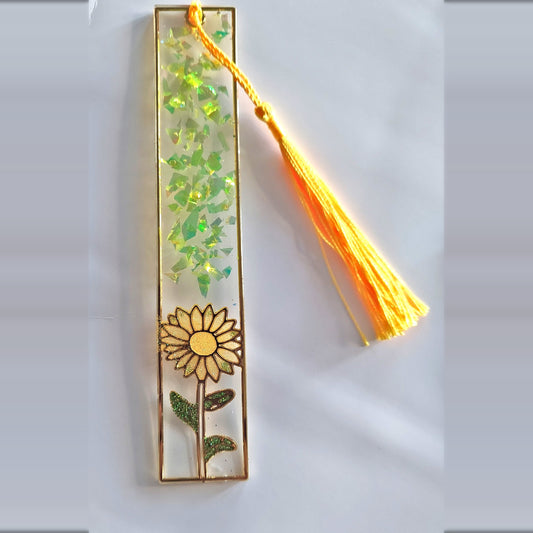Handmade yellow resin bookmark with sunflower design, iridescent glitter flakes and yellow tassel on a light background